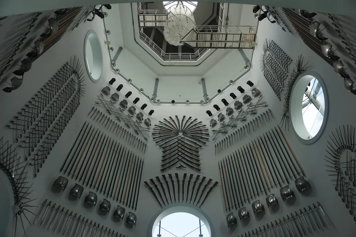 A collection of medieval weapons on display in a historic armory room with ornate design.