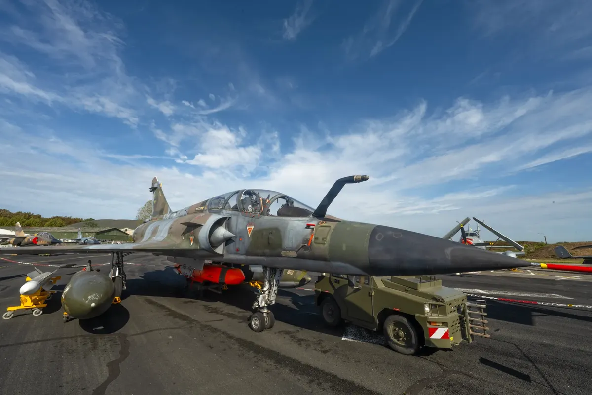 A military jet parked on an airfield with clear blue skies above, ready for service.